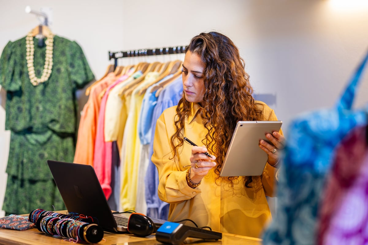 Boutique owner updating inventory on a tablet at the counter